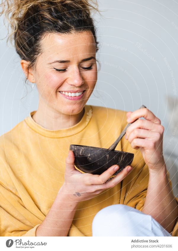 Blonde Frau mit Holzschüssel mit gesundem Essen zu Hause positiv Appartement Lächeln Lebensmittel Schalen & Schüsseln Mango Gesundheit jung Raum heiter