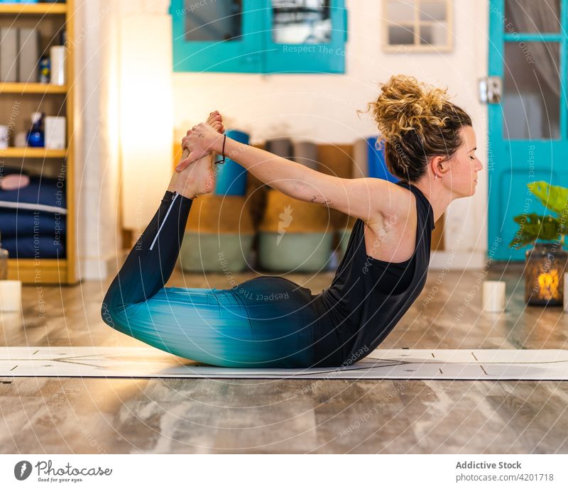 Flexible Frau in Bogenhaltung im Yogastudio Asana Konzentration Bogenstellung dhanurasana Wellness üben Atelier Wohlbefinden beweglich Zen Dehnung Energie