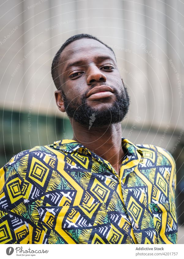 Schwarzer Mann steht auf der Straße und schaut in die Kamera freundlich maskulin Macho Ornament Porträt Großstadt schwarz Afroamerikaner ethnisch Hemd