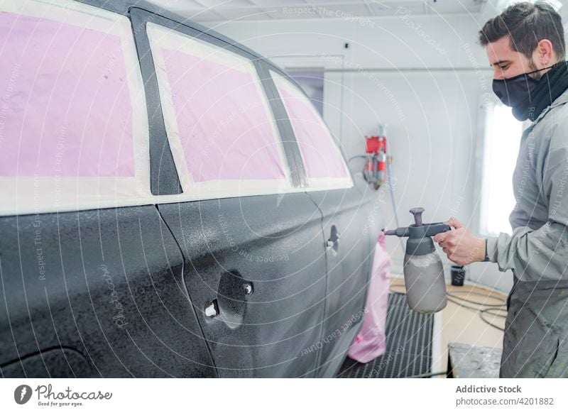 Mann mit Spritzpistole lackiert Auto in Werkstatt Farbe PKW Pistole Arbeiter Mundschutz Aerosol Spray Meister Automobil männlich Uniform Beruf Werkzeug
