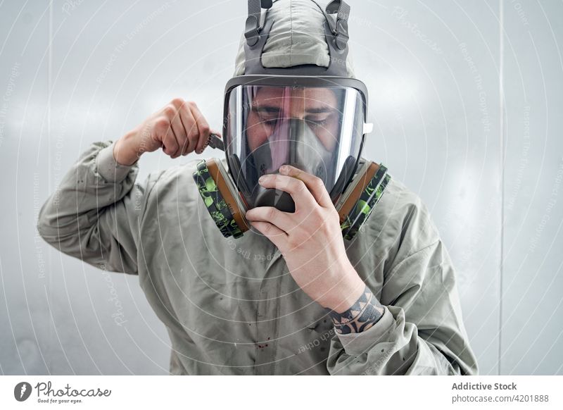 Mann in Atemschutzmaske und Anzug beim Autoservice Atemschutzgerät Farbe Werkstatt behüten angezogen Arbeit professionell Mechaniker männlich Mundschutz