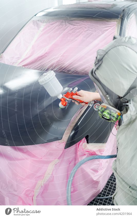 Mann in Arbeitskleidung lackiert Auto in Werkstatt Farbe Pistole PKW Aerosol Spray Atemschutzgerät behüten Arbeiter Automobil Mundschutz Meister Anzug sicher