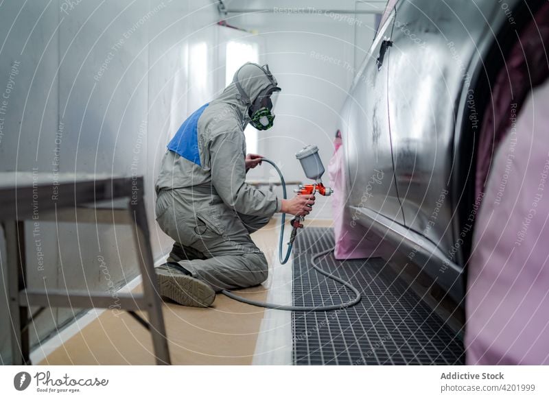 Mann in Arbeitskleidung lackiert Auto in Werkstatt Farbe Pistole PKW Aerosol Spray Atemschutzgerät behüten Arbeiter Automobil männlich Mundschutz Meister Anzug