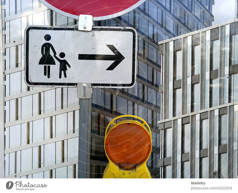 Verkehrszeichen mit Hinweis für Fußgänger und gelbe Warnleuchte vor einem Bauzaun an der Senckenberganlage im Westend von Frankfurt am Main in Hessen Mutter
