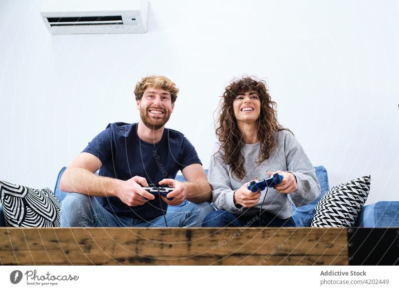 Junges Paar spielt ein Videospiel zu Hause Spiel Konsole Raum Zusammensein Glück genießen aufgeregt heiter Partnerschaft spielen Liebe Spaß Apparatur