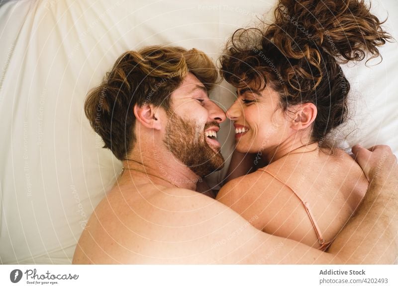 Ein Paar, das sich auf dem Bett anschaut, während es sich umarmt. Umarmung Sofa heimwärts Partnerschaft Liebe romantisch Freundin amourös jung Lügen Nachtwäsche