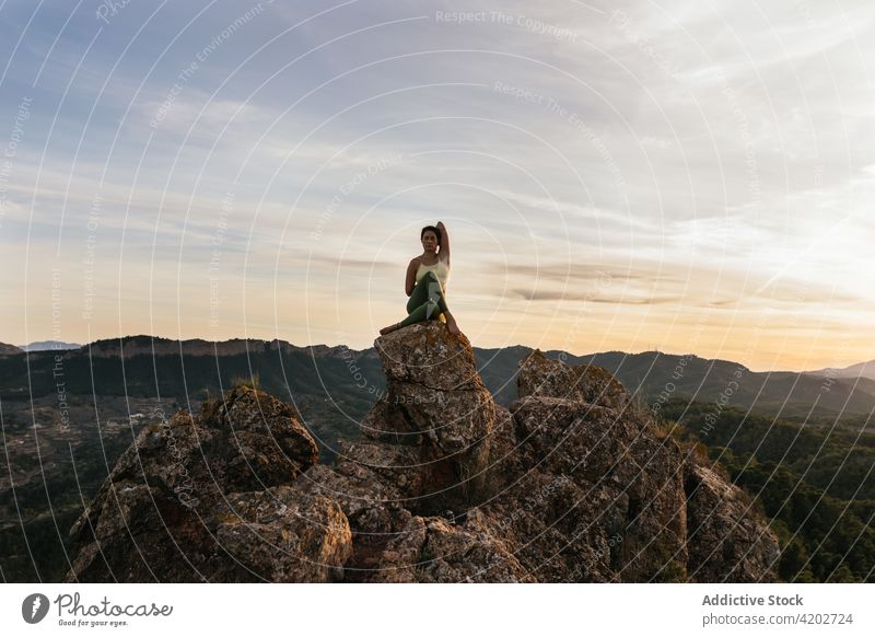 Junge Frau in Kuhgesicht-Pose auf einer Bergkuppe Yoga Sonnenuntergang Klippe Kuhgesichtshaltung Vitalität Zen üben Harmonie gomukhasana Augen geschlossen