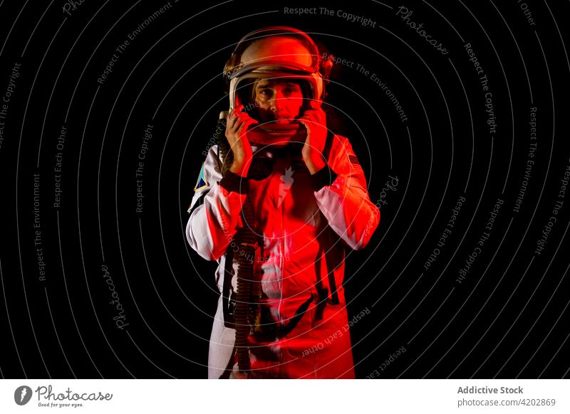 Astronaut im Raumanzug in rotem Neonlicht stehend Mann Schutzhelm professionell ernst Kosmonaut schützend Panzerung Raumfahrer Missionsstation neonfarbig Licht