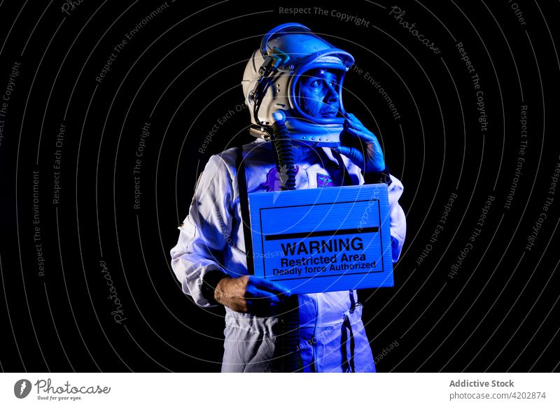 Ernster Astronaut im Raumanzug zeigt Plakat mit Warnungstext manifestieren plakatieren ernst Ermahnung Sperrgebiet tödliche Gewalt erlaubt Kosmonaut Vorsicht