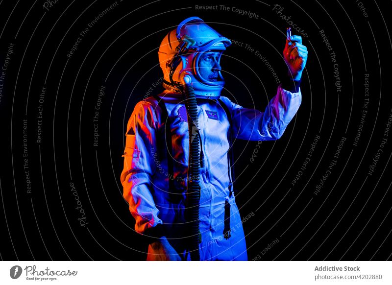 Emotionsloser Astronaut mit Blick auf eine Impfstoffampulle in der Hand Schutzhelm ernst Ampulle Raum Kosmonaut Missionsstation Astronomie Pilot Mann schützend