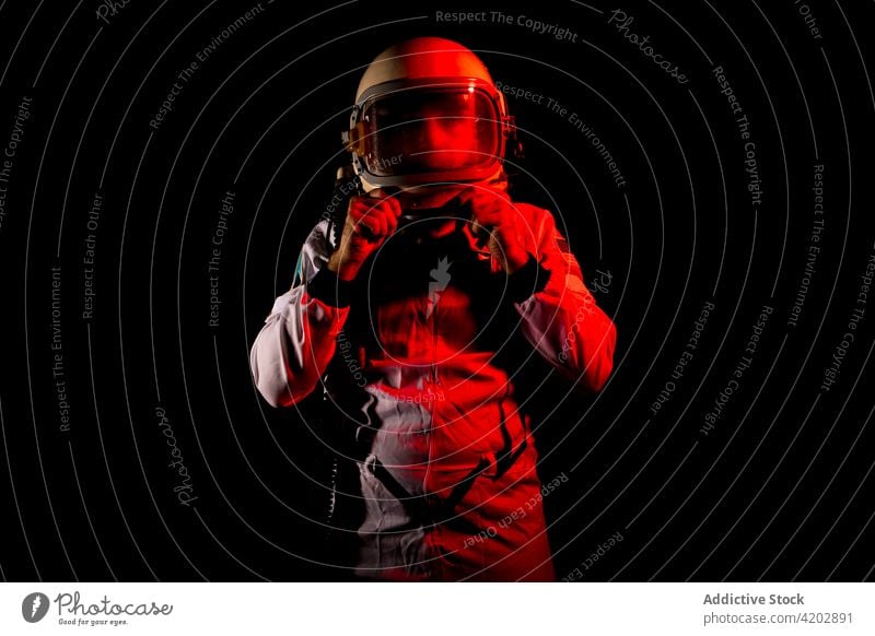Astronaut im Raumanzug in rotem Neonlicht stehend Mann Schutzhelm professionell ernst Kosmonaut schützend Panzerung Raumfahrer Missionsstation neonfarbig Licht
