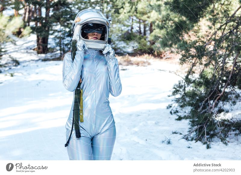 Anonyme entschlossene Frau mit Weltraumhelm in verschneitem Wald stehend Astronaut Raumanzug ernst Schnee Raumfahrerin Kosmonaut Winter Astronomie Schönheit