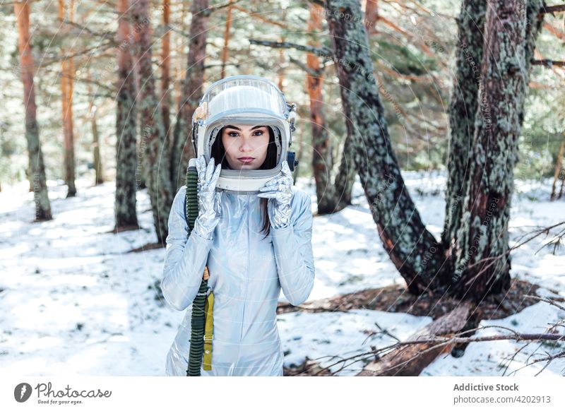 Entschlossene Frau mit Weltraumhelm in verschneitem Wald stehend Astronaut Raumanzug ernst Schnee Raumfahrerin Kosmonaut Winter Astronomie Schönheit Schutzhelm