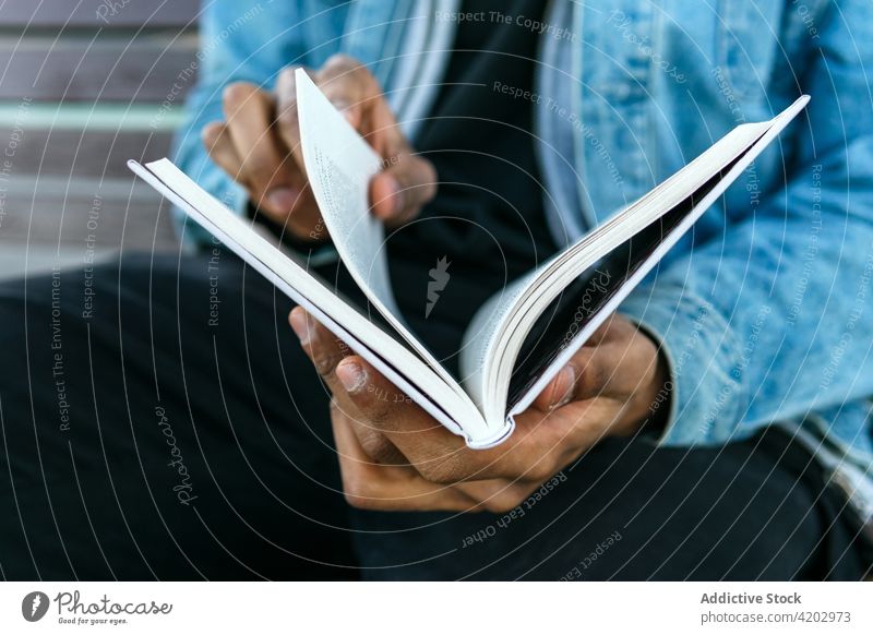 Anonymer schwarzer Mann mit Tagebuch auf einer Straße in der Stadt Journal achtsam lesen maskulin brutal Buch Macho Porträt tropisch exotisch zuschauend