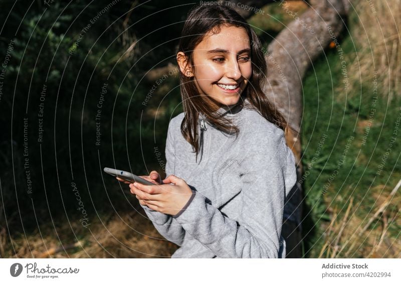 Frau mit Smartphone ruht sich beim Wandern im Wald aus Wanderer benutzend Telefon Mobile aktiv Browsen erkunden ruhen Natur Baum positiv jung Lifestyle
