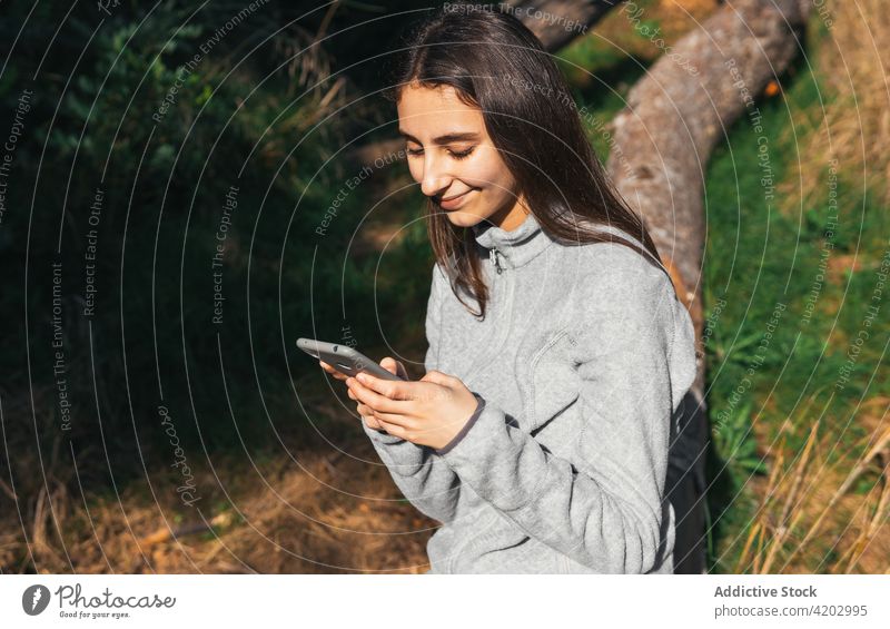 Frau mit Smartphone ruht sich beim Wandern im Wald aus Wanderer benutzend Telefon Mobile aktiv Browsen erkunden ruhen Natur Baum positiv jung Lifestyle