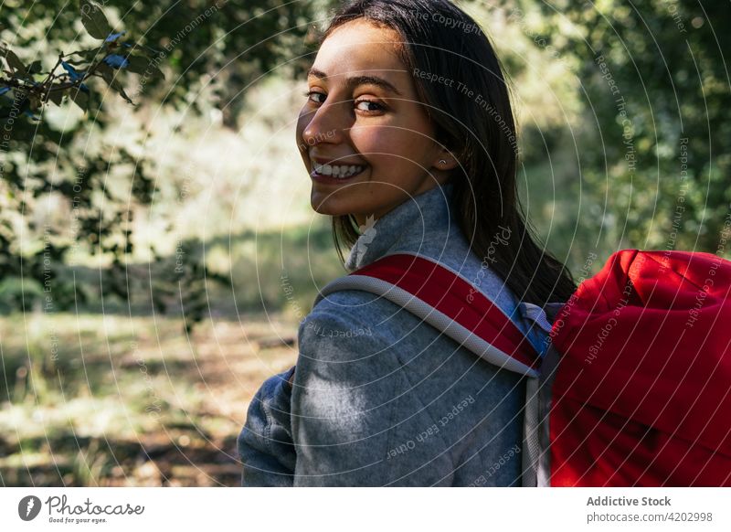 Fröhliche Frau mit Rucksack beim Wandern im Wald Wanderer Glück Sonnenlicht aktiv heiter Natur Lächeln jung Lifestyle Aktivität Erholung Wellness Gesundheit