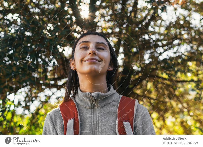 Fröhliche Frau mit Rucksack beim Wandern im Wald Wanderer Glück Sonnenlicht aktiv heiter Natur Lächeln jung Lifestyle Aktivität Erholung Wellness Gesundheit