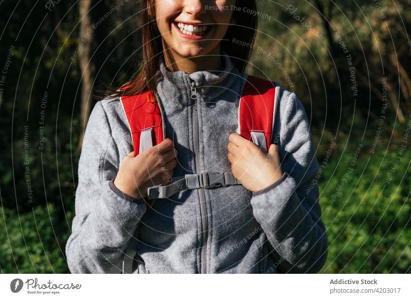 Anonyme fröhliche Frau mit Rucksack beim Wandern im Wald Wanderer Glück Sonnenlicht aktiv heiter Natur Lächeln jung Lifestyle Aktivität Erholung Wellness