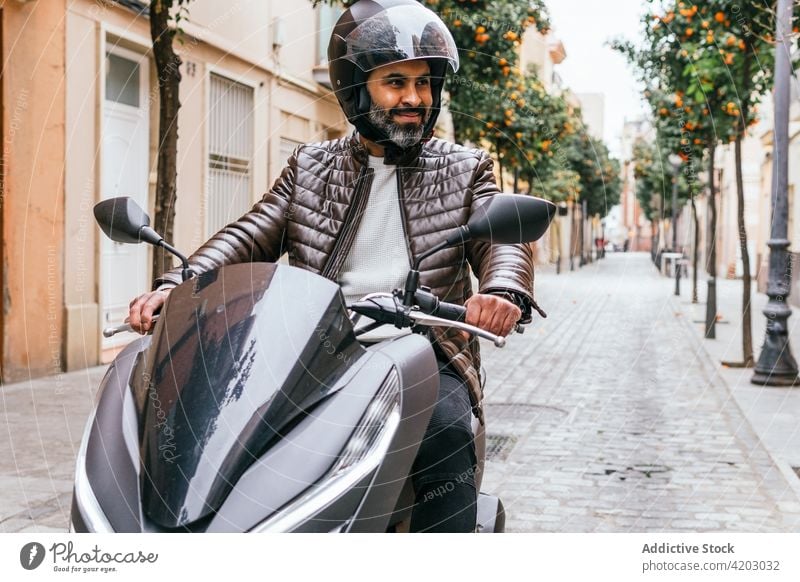 Hispanischer Motorradfahrer fährt modernes Motorrad auf einer Stadtstraße Biker Laufwerk brutal maskulin Macho ernst Mann Großstadt Porträt Schutzhelm Stil