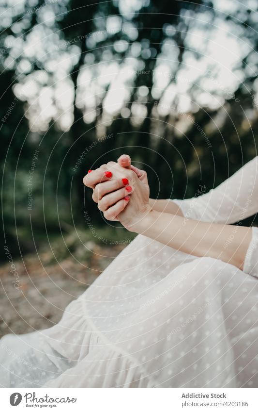 Crop Frau mit gefalteten Händen in der Natur Hände gefaltet Maniküre weißes Kleid ländlich Landschaft Park Baum Umwelt Wald rot Dame Gelassenheit Wälder