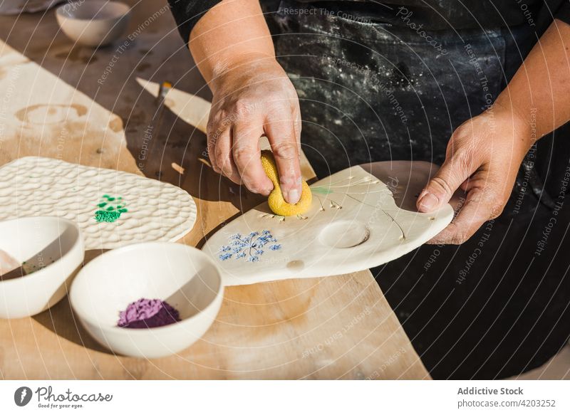 Unbekannte Frau, die eine Zeichnung auf einer Tafel mit Pulver ausfüllt Hobby Schwamm keramisches Pigment Palette Kunst Werkstatt Handwerkerin Prozess