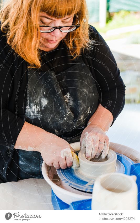 Keramiker beim Bildhauen mit Ton auf der Drehscheibe Frau Skulptur Rad Form Prozess Fähigkeit Leiste Basteln Fokus Topf Schwamm konzentriert Bildhauer