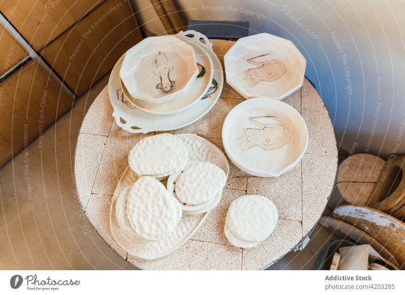 Weiße Keramikteller mit dekorativen Bildern Schalen & Schüsseln Teller Werkstatt Tonwaren Steingut sortiert Töpferwaren Handwerk Geschirr Handarbeit Utensil