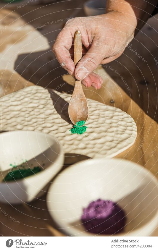 Gesichtslose Person, die Keramikpigment auf ein Tonstück aufträgt Töpferwaren keramisches Pigment Werkstatt professionell Prozess vorbereiten Pulver Kunstwerk