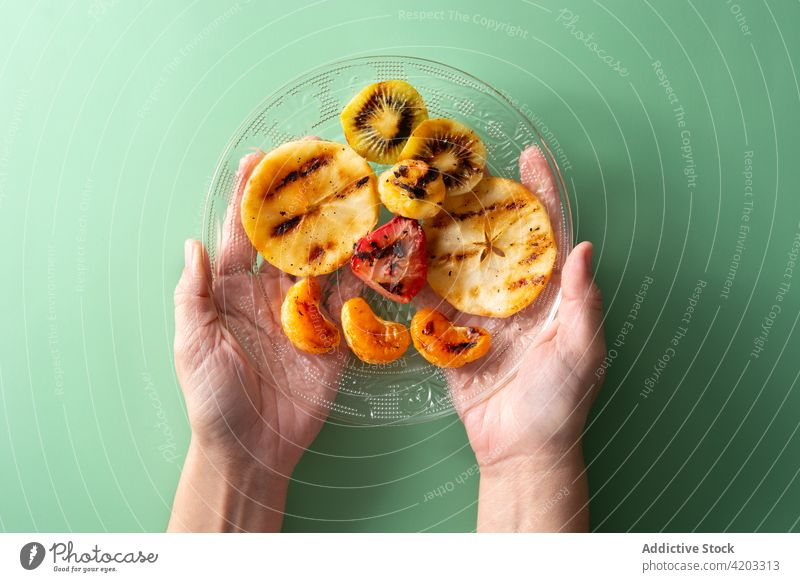 Frau hält gegrillten Obstteller in den Händen Apfel Banane Barbecue Dessert Essen Lebensmittel Frucht Gesundheit Beteiligung Kiwi mischen orange Teile Teller