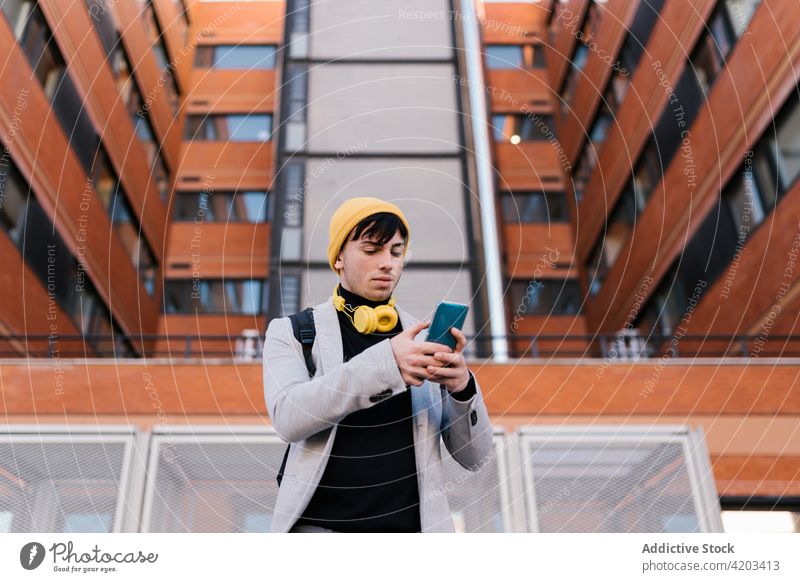 Stilvoller Mann mit Smartphone in der Stadt Schüler Großstadt Hipster Straße männlich Rucksack urban gutaussehend selbstbewusst Kopfhörer trendy jung Typ modern