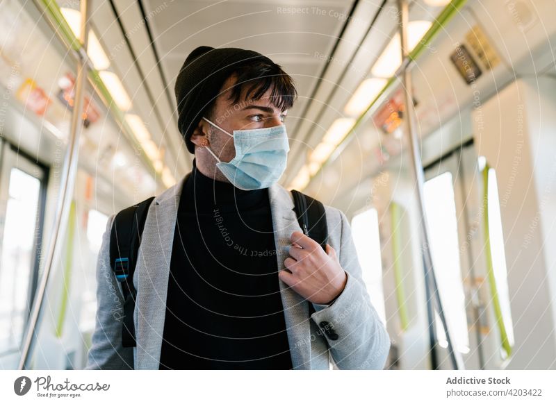 Mann mit Gesichtsmaske im modernen Zug Arbeitsweg Wagen Schüler Rucksack Verkehr leer Öffentlich männlich Zeitgenosse Mitfahrgelegenheit Passagier urban Stil