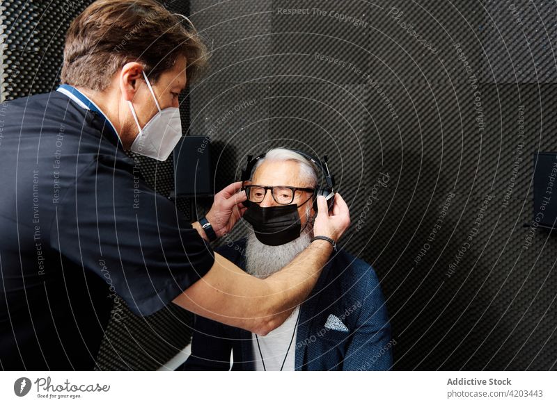 Arzt bereitet älteren Patienten auf eine audiologische Untersuchung vor hören prüfen Audiologie Prüfung geduldig vorbereiten Diagnostik Senior untersuchen