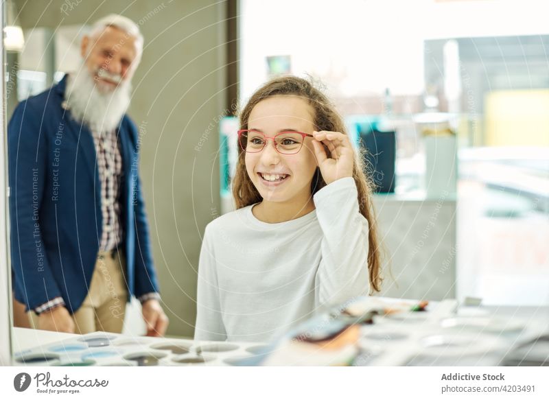 Mädchen wählt in einem Optikgeschäft eine neue Brille aus anprobieren wählen Optiker optisch Laden Großvater Enkelin Zusammensein Senior heiter