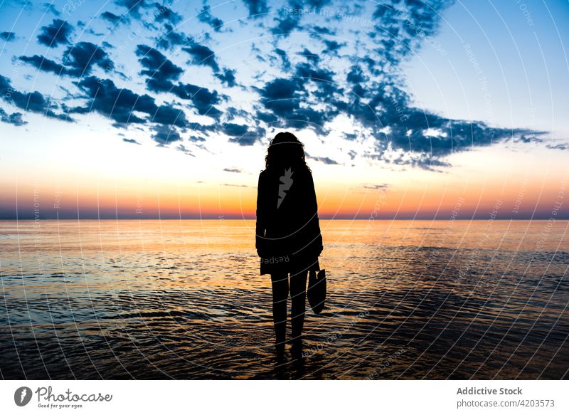 Anonyme Frau vor dem Meer und Sonnenuntergang Himmel stehen Silhouette MEER Dämmerung bewundern Sommer farbenfroh Wasser ruhig Landschaft Abend spektakulär