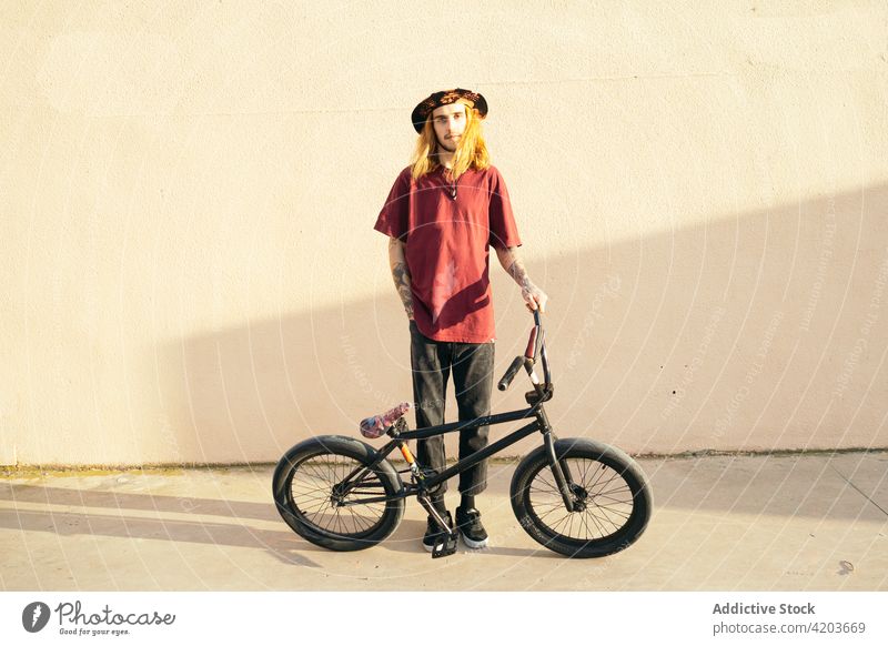 Tätowierter Biker mit BMX-Fahrrad auf dem Bürgersteig Testversion Hipster bmx Sport Individualität cool Hand-in-Tasche Mann Straßenbelag modern Stil kreativ