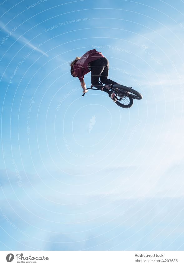 Anonymer Sportler, der während des Trainings auf ein Trialbike springt Radfahrer Testversion springen Fahrrad bmx extrem Freestyle Adrenalin Mann Blauer Himmel