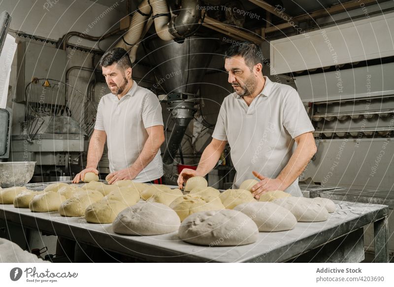 Ethnische Bäcker bereiten am Tisch in der Küche Brot zu vorbereiten Formular Teigwaren professionell Kollege natürlich Männer Bäckerei ethnisch Mitarbeiterin