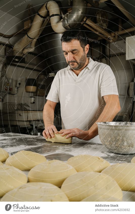 Ethnischer Bäcker bereitet Brot am Tisch in der Küche zu Mann vorbereiten Formular Teigwaren professionell natürlich Bäckerei ethnisch Schalen & Schüsseln Mehl