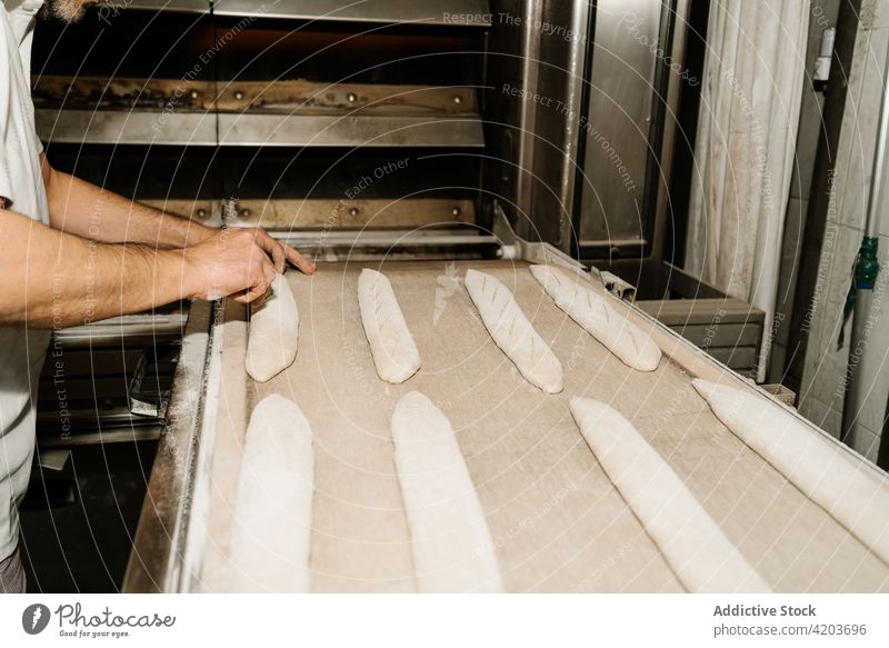 Bäckerin bereitet Brot auf einem Tablett in einer Bäckerei vor vorbereiten Teigwaren geschnitten roh natürlich Mann ähnlich professionell Gerät Arbeit Prozess