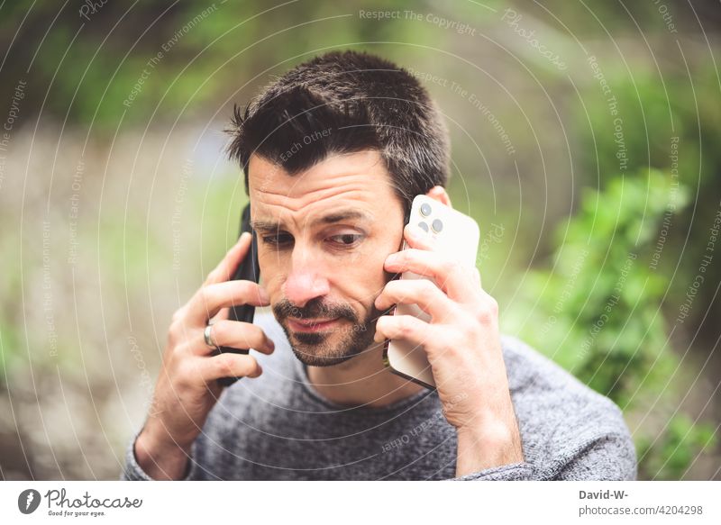 mit zwei Handys telefonieren - mulitasking multitasking Stress Mann Mobile Gespräch dual zuhören Erreichbarkeit