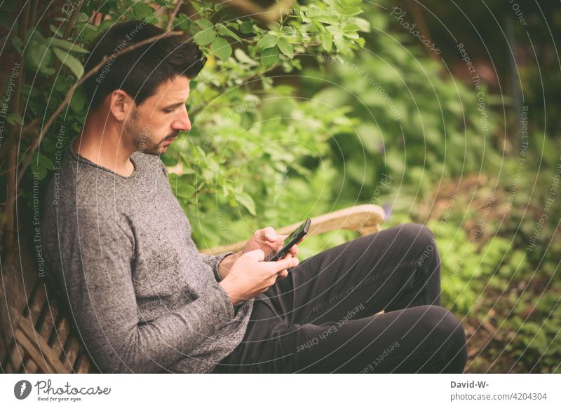 Handy in der Hand Mann Hände tippen draußen sitzen ruhe lesen vertieft online Lifestyle Smartphone