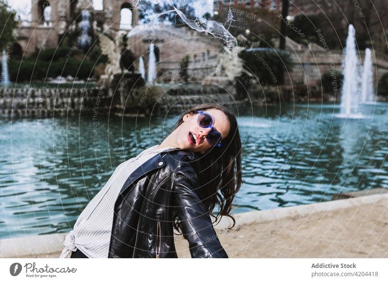 Unbekümmerte Frau im Stadtpark in der Nähe eines Brunnens sorgenfrei ausdehnen Freiheit Park Großstadt schlendern Gelassenheit Stil Outfit trendy Sonnenbrille