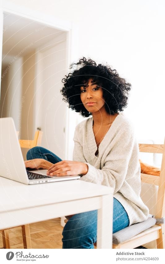 Zufriedene schwarze Frau sitzt am Tisch mit Laptop freiberuflich heiter heimwärts Büro Unternehmer Projekt ethnisch Afroamerikaner Gerät Apparatur abgelegen
