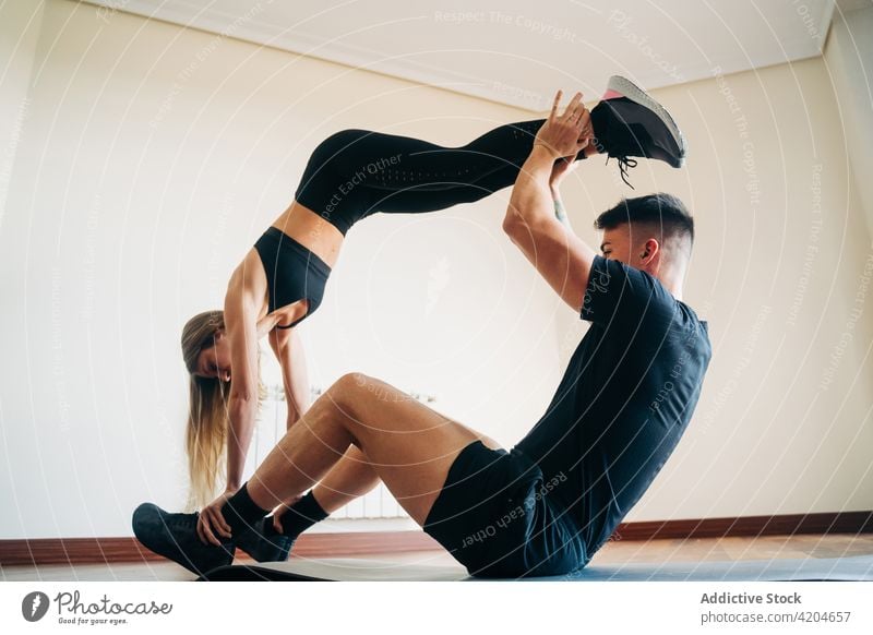 Flexibles Paar bei Acroyoga-Übung Akro-Yoga Training Gleichgewicht Fitness üben gymnastisch akrobatisch abstützen Frau Sportkleidung Athlet Raum Unterlage