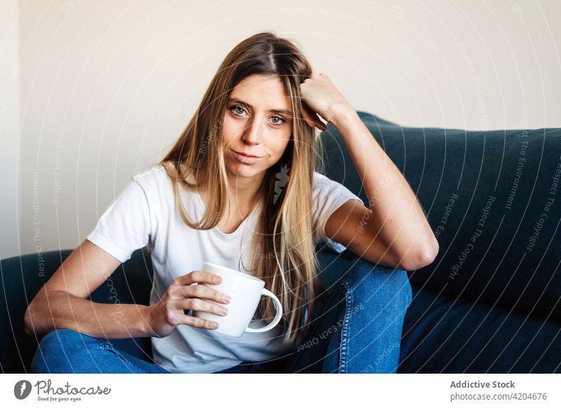 Ruhige Frau mit Tasse auf Sofa Liege trinken Getränk Kaffee Becher sich auf die Hand lehnen angewinkeltes Bein Dame besinnlich Lifestyle sich[Akk] entspannen