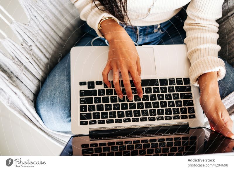 Anonyme junge Frau, die in der Hängematte sitzend am Laptop arbeitet freiberuflich Browsen Apparatur soziale Netzwerke benutzend Komfort Netbook Surfen online