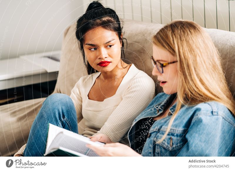 Junge Freundinnen, die sich auf der Couch unterhalten Frauen Kommunizieren heiter Gespräch Schüler nachdenklich diskutieren Zeit verbringen multiethnisch