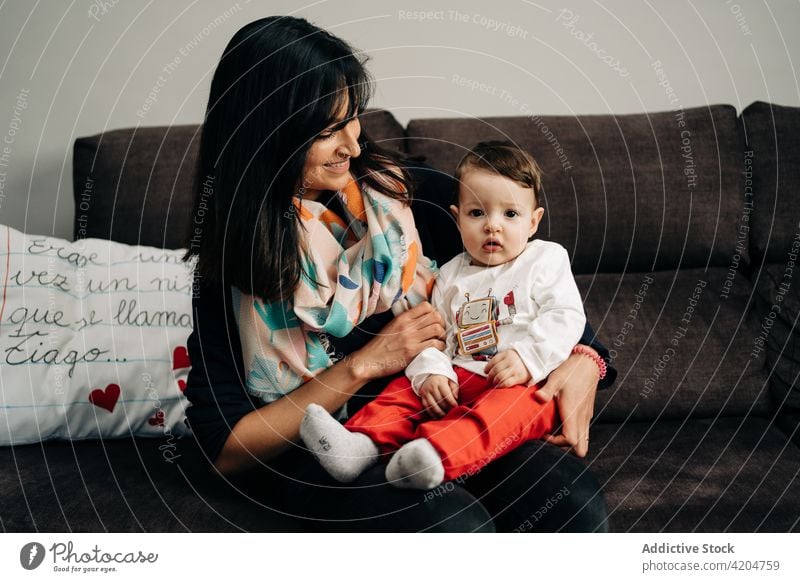 Multiethnische junge Mutter mit entzückendem kleinen Sohn auf der Couch Frau Kind Sofa Lächeln Freude Zusammensein Liebe Zeit verbringen Glück Kleinkind