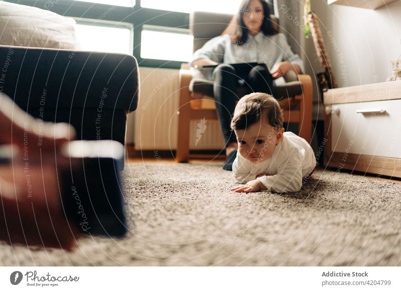 Baby krabbelt auf dem Boden in der Nähe der Eltern zeigt Cartoon auf Smartphone krabbeln Stock niedlich zuschauen Wohnzimmer Kind süß Anschluss Gerät Teppich